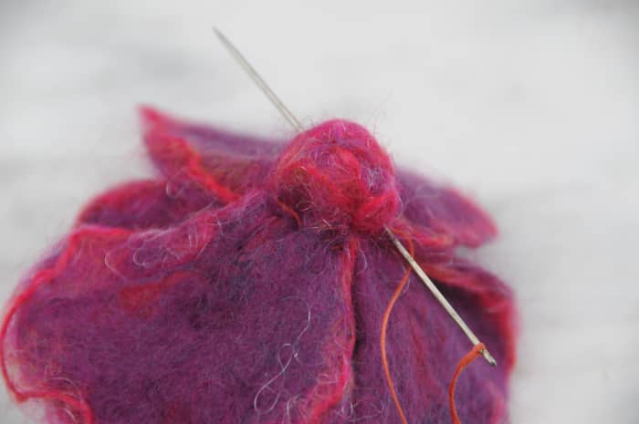Sew right though the back of the flower from several points as shown and remove elastic band.