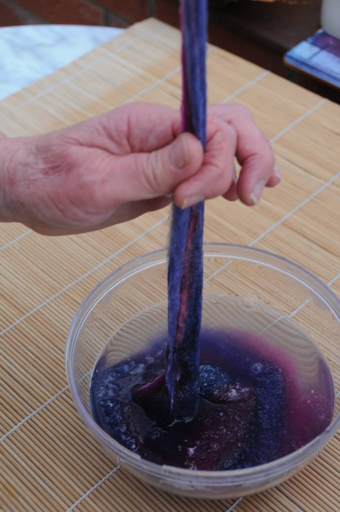 Remove any excess water by running your fingers down the length of the piece of roving and letting the water fall back in the bowl.