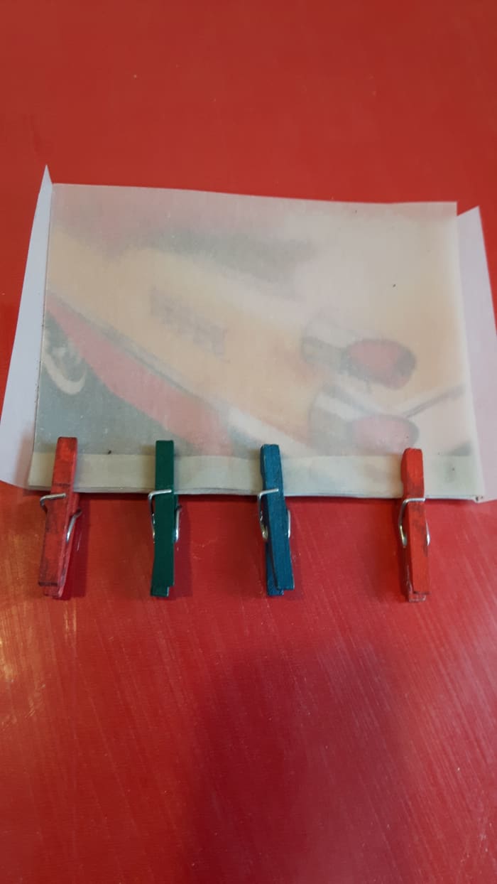 Apply glue to a tab and clip it with clothespins so the edges stick together and don't buckle. Here, the front and the bottom are gluing.