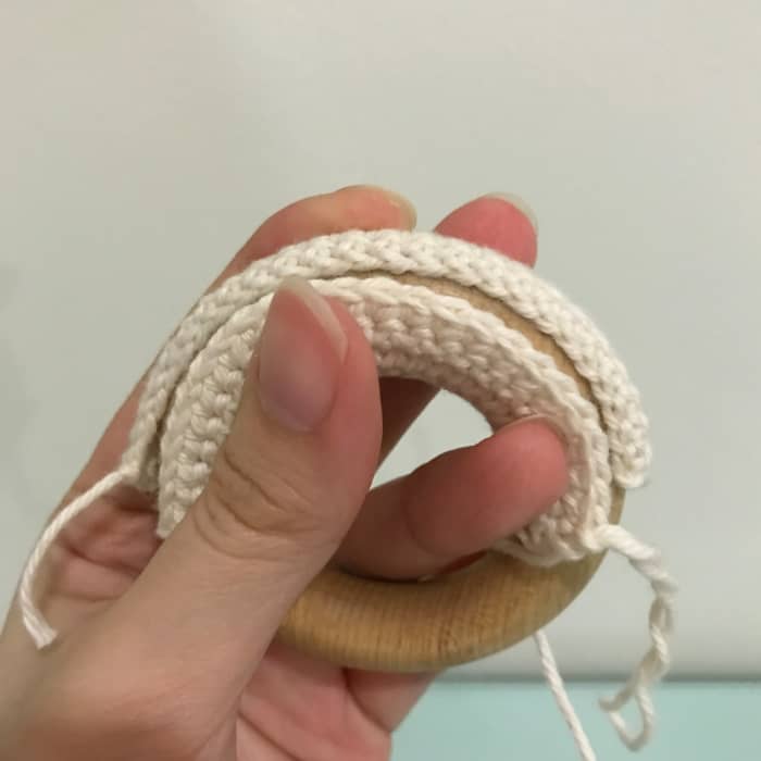 Once the rectangular piece can completely cover the wooden ring, fasten off and sew the piece closed with the tail end.