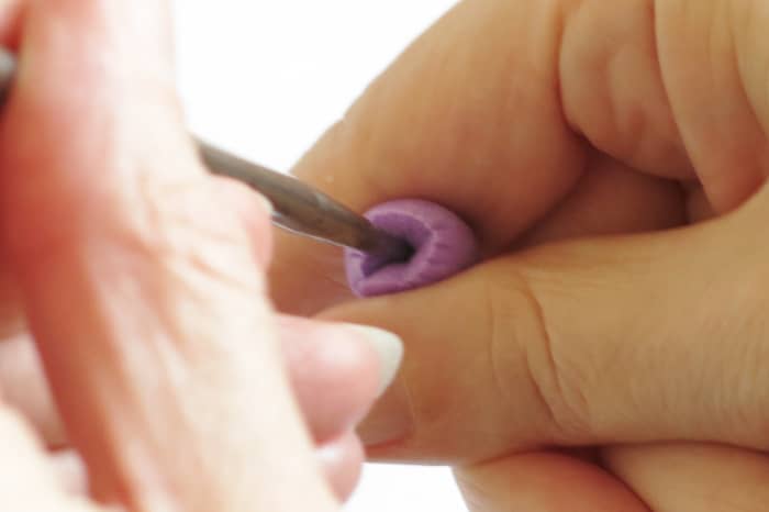 Holding the rounded end of your earplug, take your pointed tool and drill it into the flat end of your cut earplug.