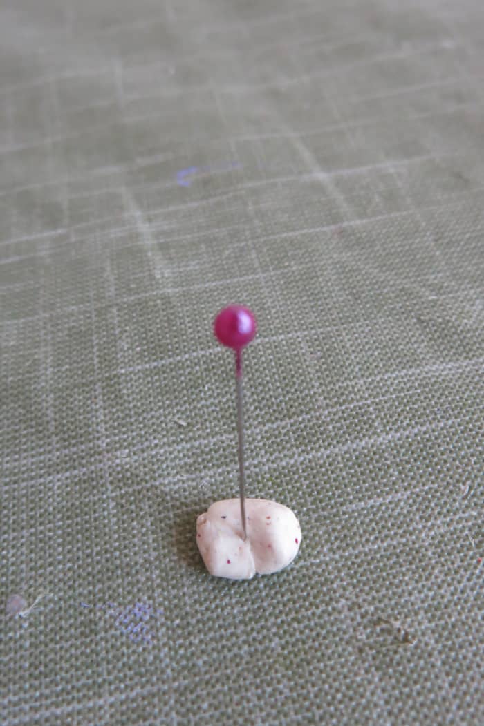 Bake a small piece of clay with a pin stuck into it to test whether the ball on the pin can withstand the heat from the oven.