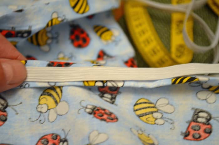 Lay the elastic on top of the turned down hem, then sew around stretching elastic as you go.
