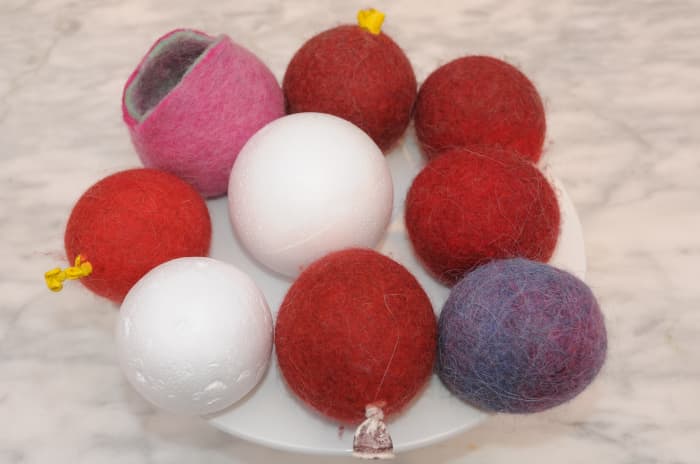 A group of wet felted coin purses which were all made at one sitting, alongside two polystyrene balls.