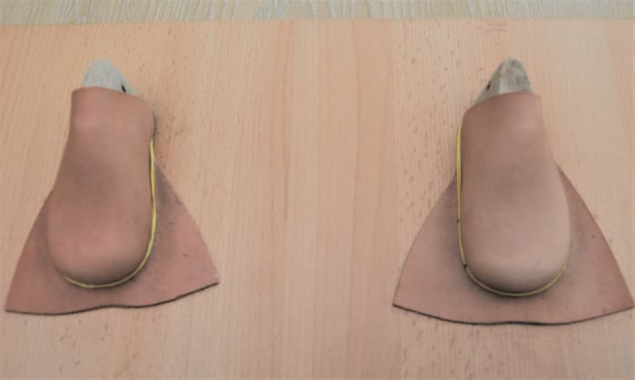 Scrap pieces of wet leather molded to the shoe lasts. Attach elastic bands and leave overnight to dry.