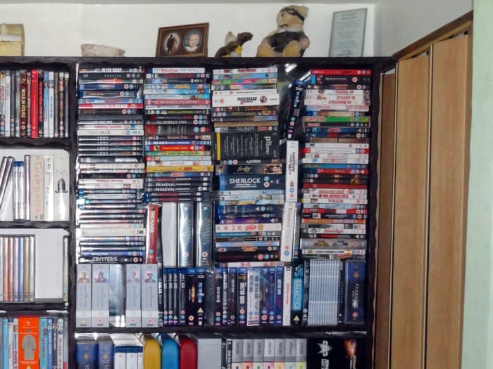 DVDs and Blu-ray discs are stacked on top of each other in the top right-hand corner, creating a need for additional shelving.