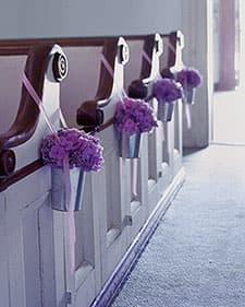 These metal sap buckets filled with flowers and hung by ribbons make for creative and cost-effective pew markers.