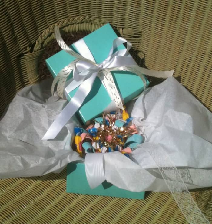 The long lace pieces of ribbon were tied into a bow, securing the corsage on the wrist. White tissue paper protected the corsage inside the white and gold-ribboned box.