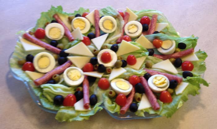 A traditional antipasto platter that includes eggs, salami, cheese, tomatoes, olives, and lettuce.