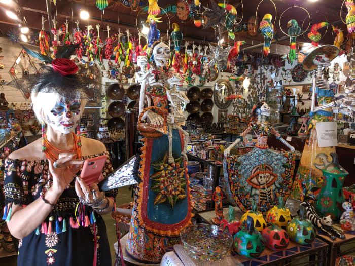 My wife preparing to take a picture of the el Dia de los Muertos merchandise surrounding her
