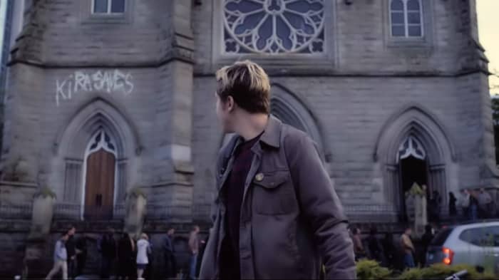 "Kira saves" is spray painted on a building, showing support for the mysterious entity bringing criminals to justice in 'Death Note' (2017), a Netflix adaptation.