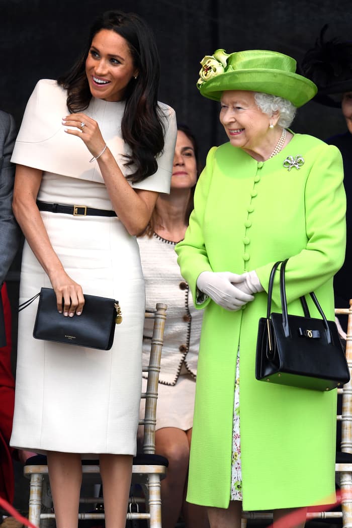 Meghan Markle, the Duchess of Sussex, carries a clutch. Queen Elizabeth is seen with her iconic handbag.