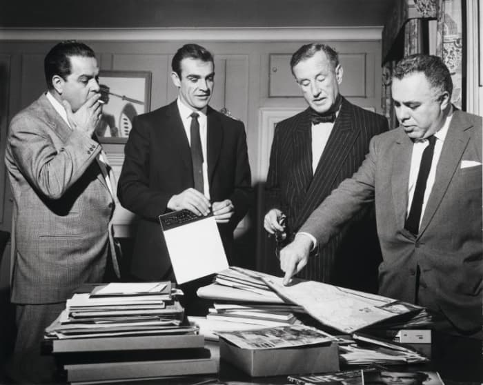 During the filming preparation of "Dr. No," Cubby Broccoli, Sean Connery, Ian Fleming, and Harry Saltzman look at a map of Jamaica.