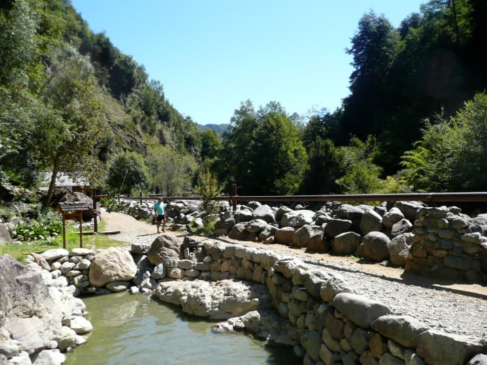 The natural appearance of the hot springs is retained at the Termas de Los Pozones. The river is beyond the built up wall.