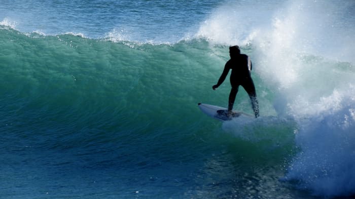 Portugal is known for its long, surfable coast. This image shows a surfer riding a wave at Praia da Poça near Estoril, Portugal.