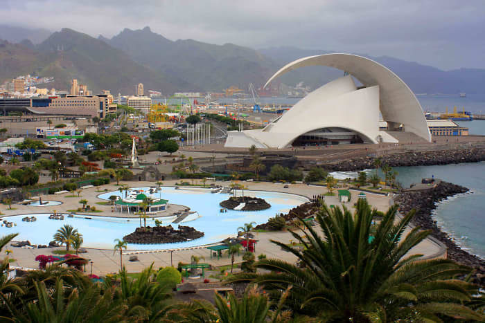 The mountains of Anaga, the Parque Maritimo Cesar Manrique and the distinctive architecture of the Tenerife Auditorium, with Palmetum palms in the foreground