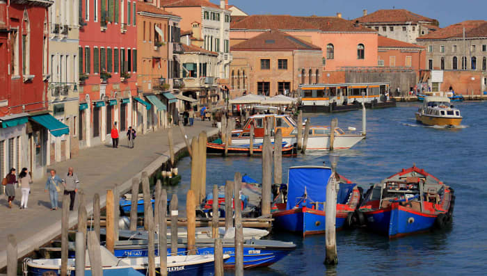 The pavements of Murano are lined with cafes and restaurants, souvenir shops and - of course - numerous ornamental glass retail outlets. This waterway is the Canale Ponte Lungo. In the distance is the vaporetto water bus station of Murano Museo