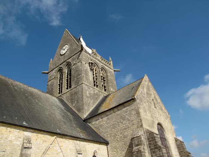 The church in Saint-Mere-Eglise where US paratrooper John Steele was caught in the church steeple. If you look closely you can see a parachute and dummy marking the spot.