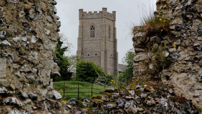 The stonework of the 12th century Castle Acre Priory, and in the distance the 15th century Church of St James the Great