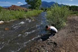Red Willow River (drinking water on the pueblo) with pueblo and Taos mountains in the background.