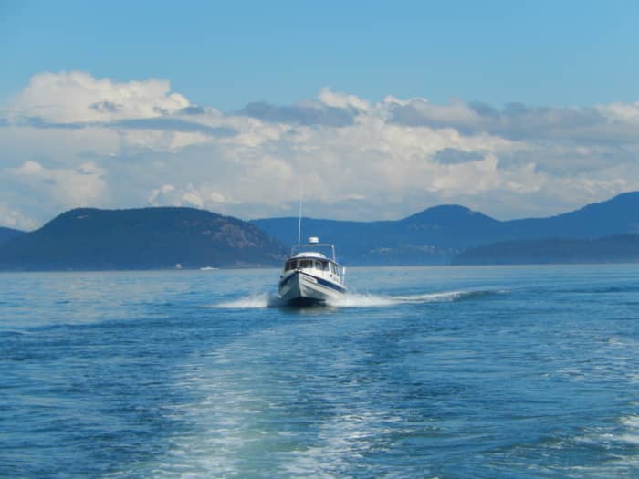 A C-Dory, a small pocket cruiser, crossing Rosario Strait, with some of the San Juan Islands in the background.