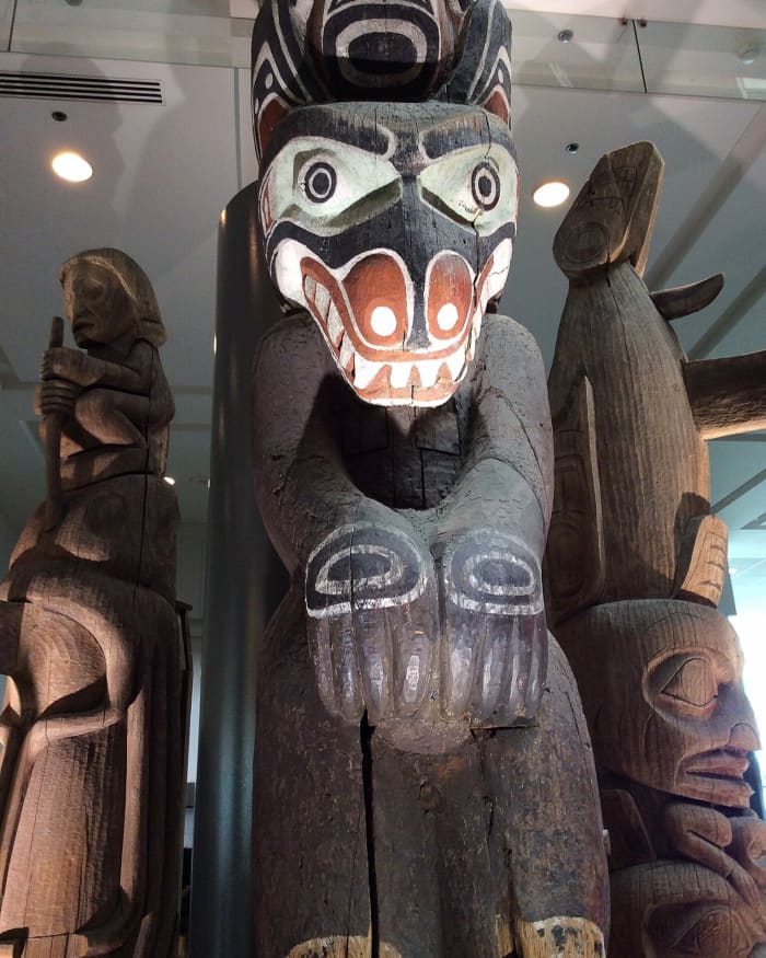 This is a close-up view of the three totem poles in the Vancouver Convention Centre. The middle pole is very tall and extends to the second storey of the building.