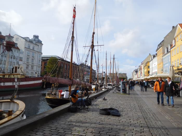 Diners at outside cafes being entertained by a guitarist in Nyhavn Harbor in Copenhagen.