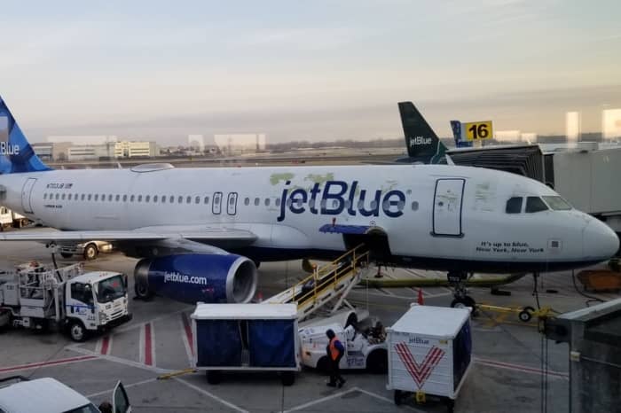 This JetBlue plane has seen better days. Some paint issues are visible near the front of the aircraft and around the JetBlue logo.