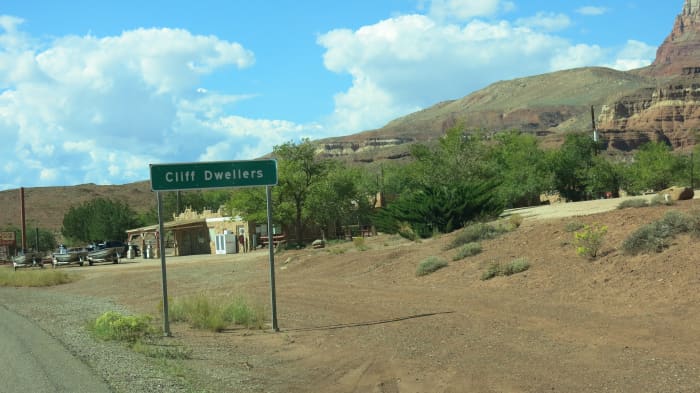 Road sign announcing Cliff Dwellers with gas station in background as you round the bend after passion the field of boulders and original rock structures.