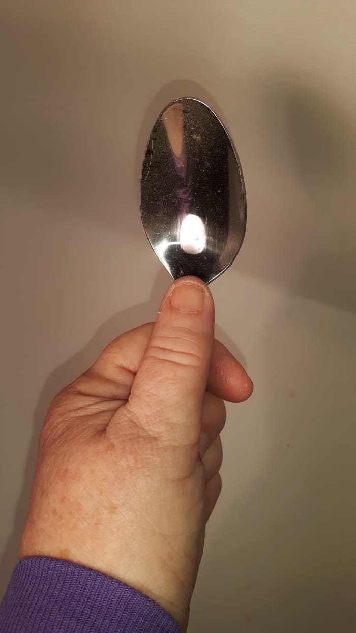 Look intently at the spoon. With your thumb, slowly rub the neck of the spoon up and down.