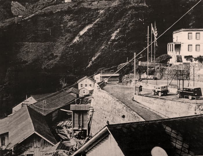 View to left of mill site, showing US Consulate at upper right, with flags.