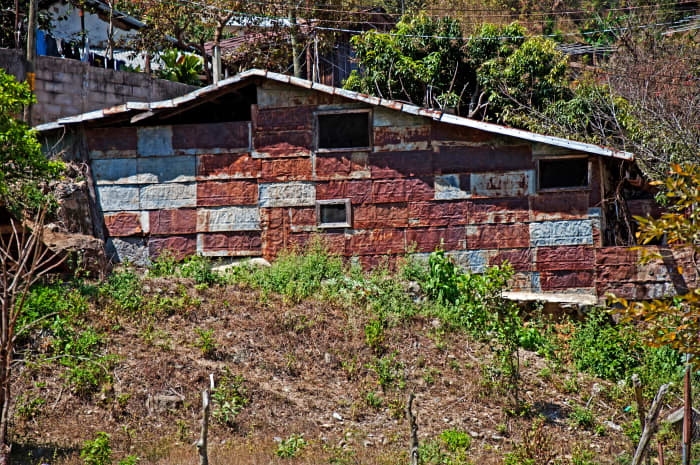 Abandoned dwelling that has been repaired with explosive-barrel siding.