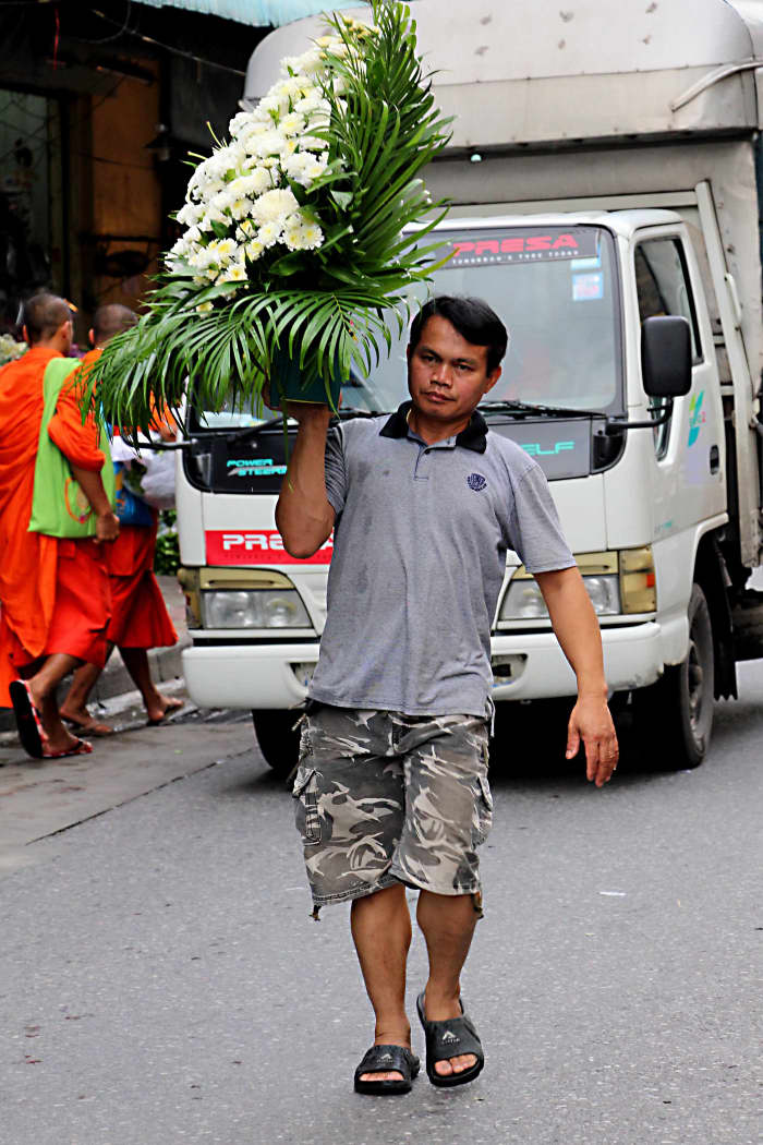 Two monks walk in the background, whilst a flower seller walks down the middle of the street with an impressive display - just 3 of the 8 million people of this great city