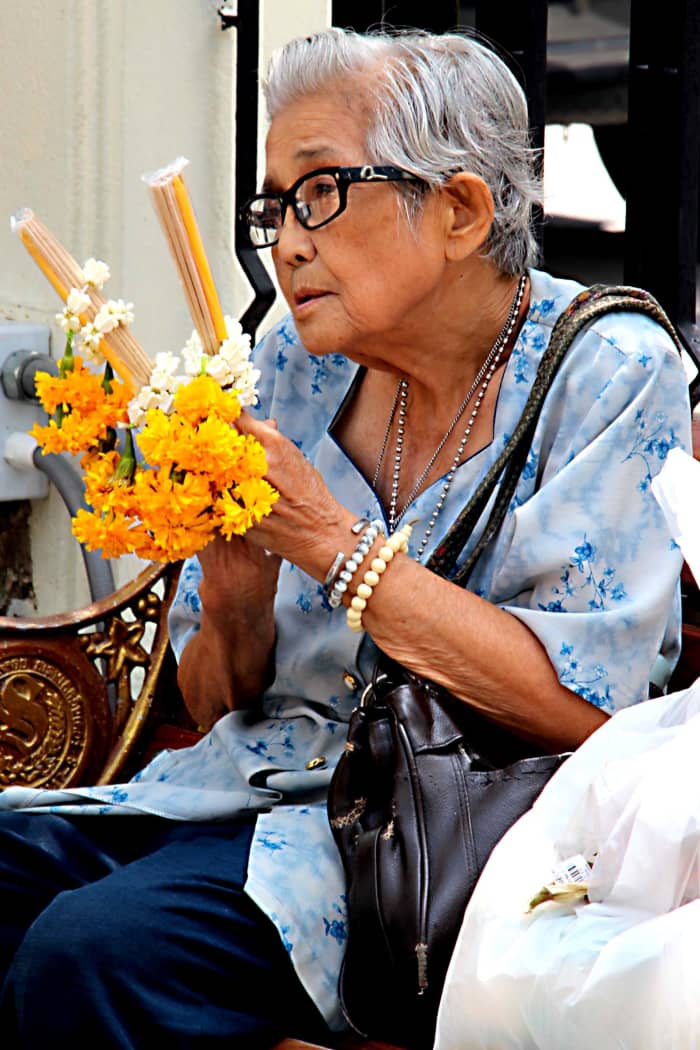 An elderly woman makes offerings at the Erawan Shrine - site of a terrorist bombing just one month before this photo was taken, but soon restored to its status as a hugely popular site of devotion and prayer for shoppers and workers in the city.