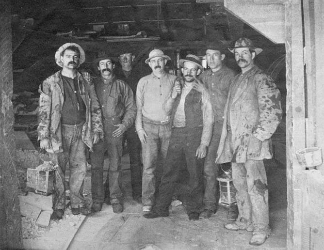 Caption on image: "To Labor is to Pray." Frances S. Osgood. Photograph of seven men, Comstock miners, two holding lanterns; from the Alfred Doten collection; cyanotype.