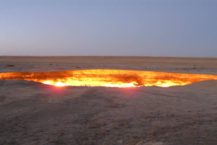 A fiery doorway to Hell that burns amid a barren desert landscape.