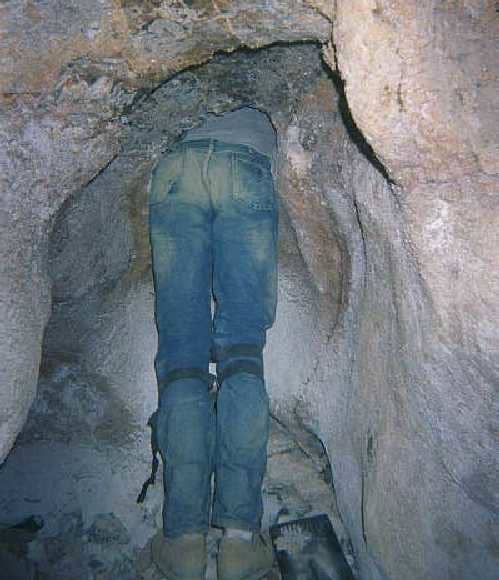 Ted the Caver, fitting himself into the hole that he and a friend opened up to explore an unknown cave.