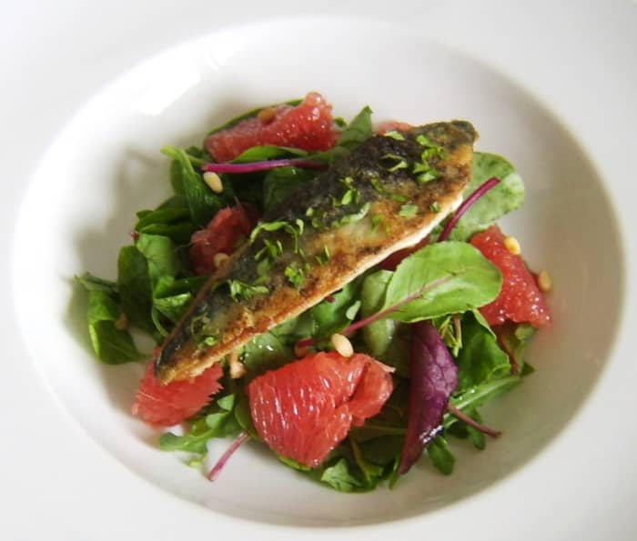 A simply and quickly pan fried mackerel fillet is served on a bed of mixed green salad leaves, red grapefruit and toasted pine nuts