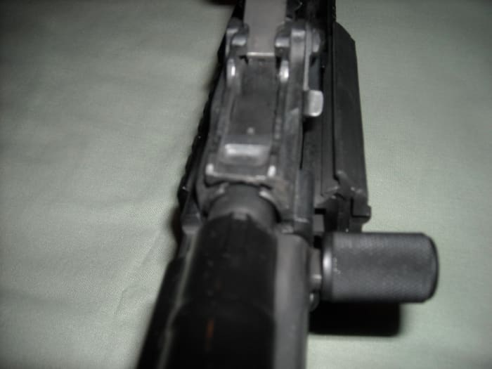 Fold the rear sight forward and seat the front end of the dust cover into the notched area below the rear sight. While applying forward pressure to the notched area, push down firmly on the rear of the dust cover to properly lock into place the dust