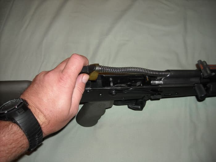 Push in on buffer spring assembly and push towards muzzle, then lift and remove buffer spring assembly.