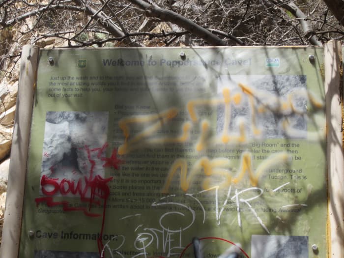 Graffiti covered sign at entrance to Peppersauce Cave in Santa Catalina Mountains near Tucson, AZ
