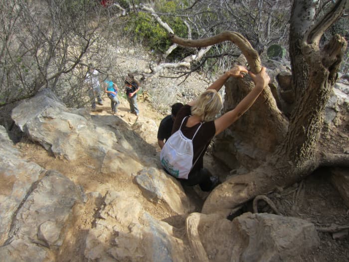 My wife climbing down from the ledge on the side of the hill where the cave entrance is located.