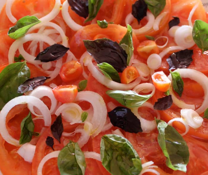 Mixed tomatoes, sliced onion, green and purple basil leaves with olive oil and white wine dressing