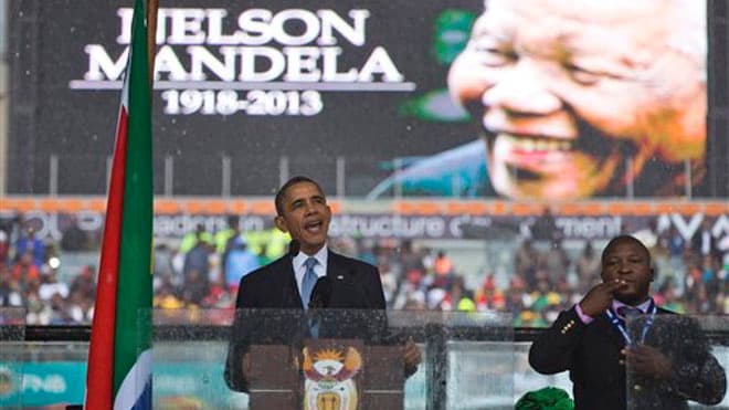 Fake Signifier and Signaler: President Barack Obama waves standing next to the sign language interpreter after making his speech at the memorial service for former South African president Nelson Mandela at the FNB Stadium in Soweto near Johannesburg,