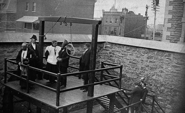 John Radclive (by the right upright) does his work in 1902 before an appreciative audience on roofs and telegraph poles.