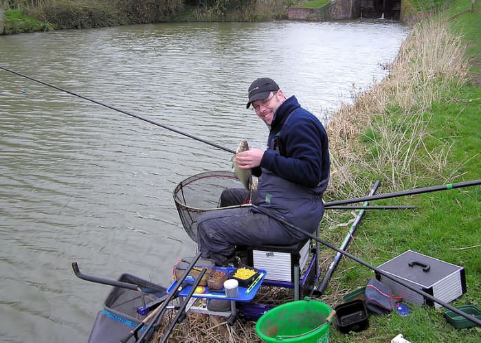 An angler displays his catch on a wide part of the Kennet and Avon Canal at the top of the Caen Hill Locks, in Devizes, Wiltshire, England.