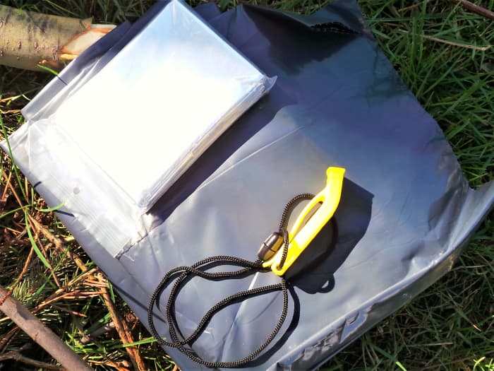 A whistle, garbage bag and space blanket are essential items to keep in your pack. As you can see, a space blanket can double as a reflective signaling device.