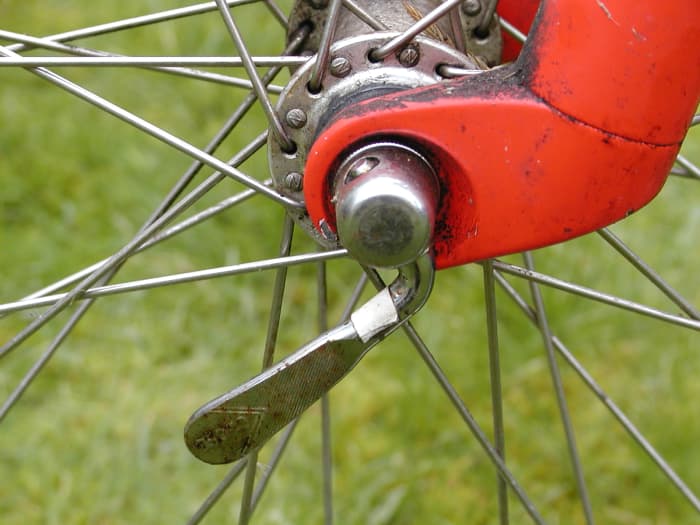 Some wheels are held on by quick release levers. The lever will hang down when loosened. Push it back upwards parallel and in line with the fork when re-tightening.