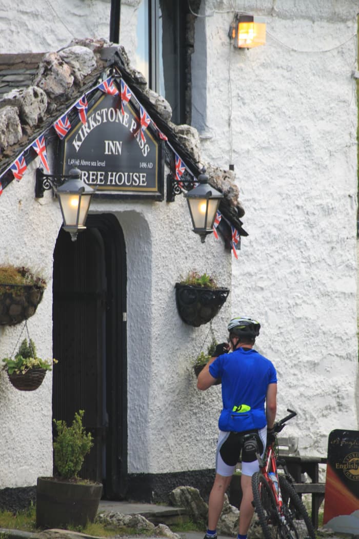 A cyclist grabbing a drink outside the Kirkstone Pass Inn after complting the highest pass in the Lake District