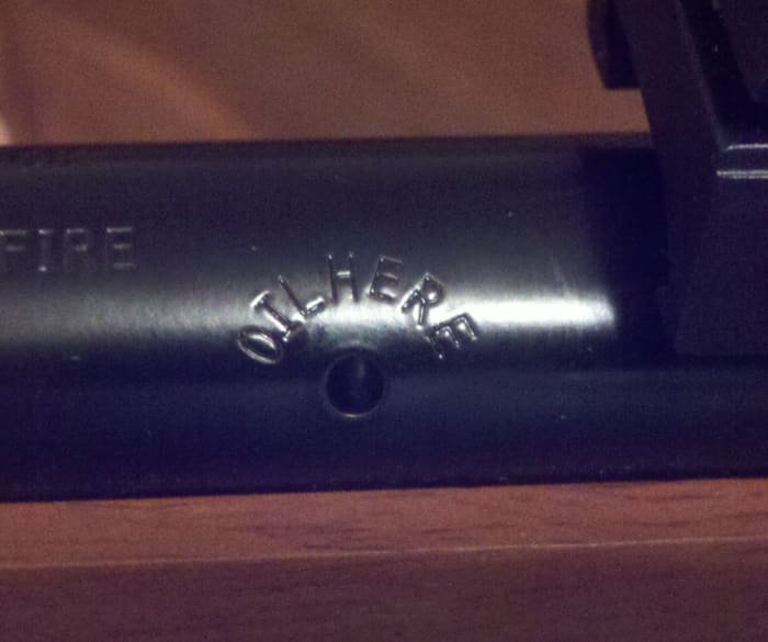 Left side, base of the barrel just before the receiver.